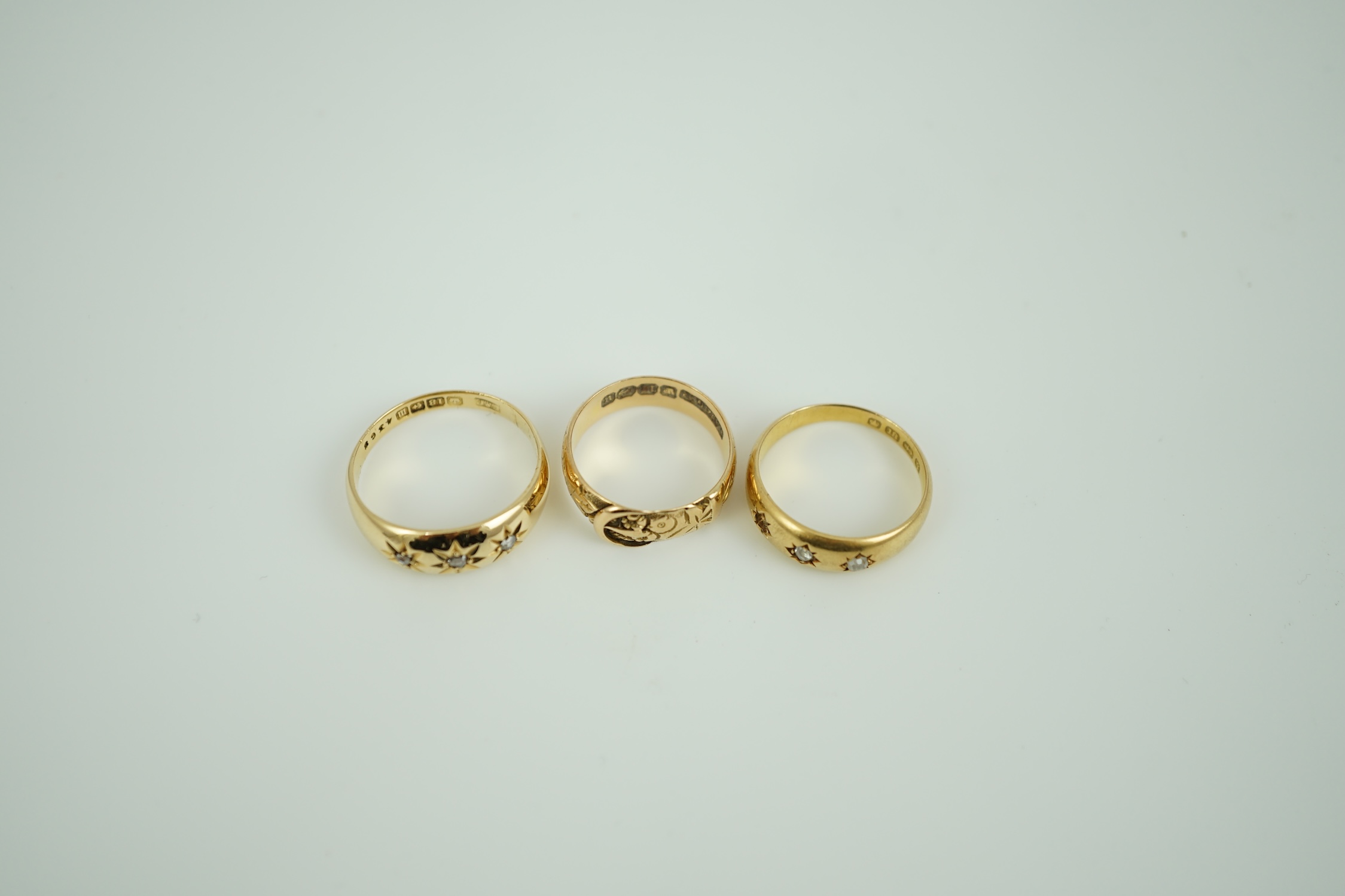 A Victorian 18ct gold buckle ring, size K/L, a Victorian 18ct gold and gypsy set three stone diamond ring (stone missing) and a later 18ct gold and gypsy set three stone diamond ring